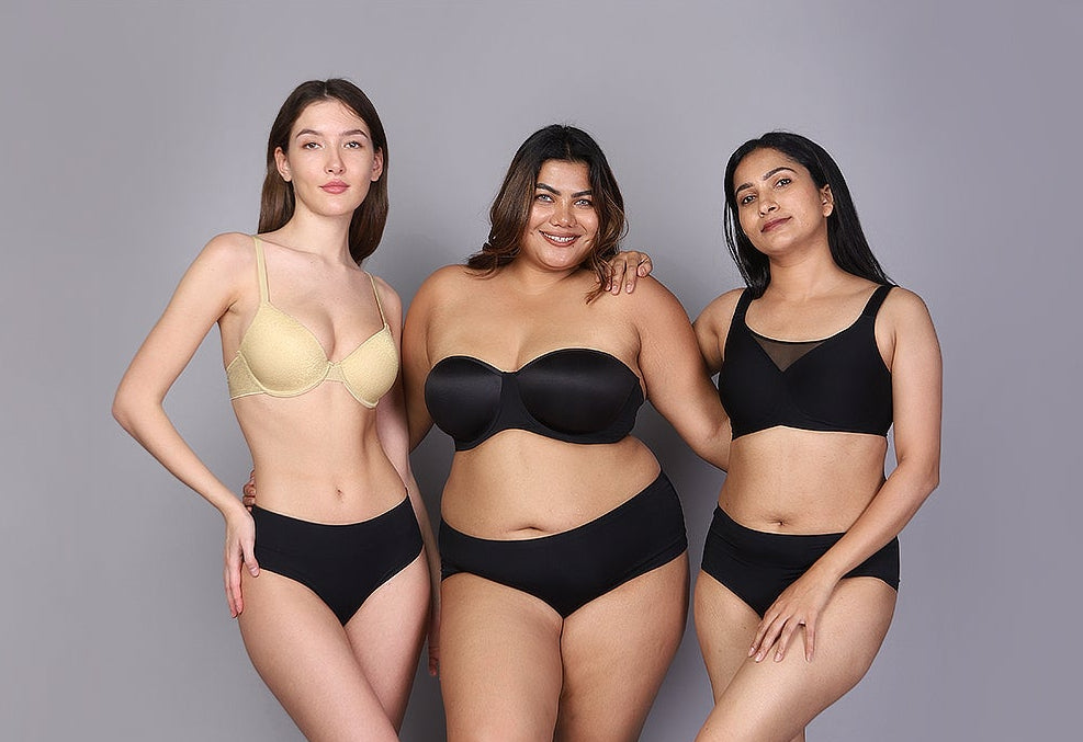 Three women wearing black lingerie on a gray background